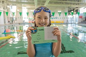 Child holding their swimming certificate at Fountain Park