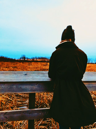 A woman gazes across a pond from a boardwalk