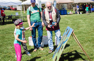 Children play a beanbag throwing game at the Riverfest