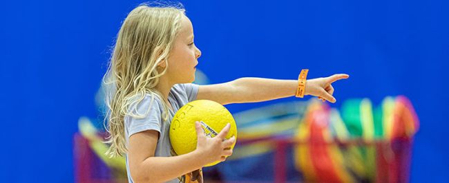 Little girl points at competition while playing dodgeball