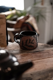 A black and brown mug on a rustic wood table.