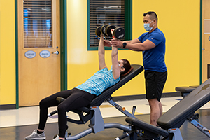 Photo of Gregory and Joanna lifting weights in the fitness centre.