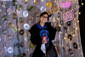Amplify Committee Member Ash Halinda posing in front of the Illuminate 2020 photo booth