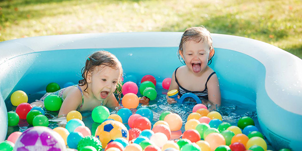 Kids playing in outdoor inflatable pool with toys