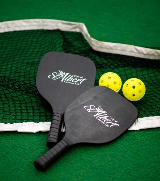 An image of two City of St. Albert pickleball paddles and 2 balls
