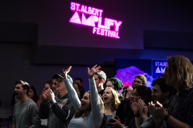 Youth in a crowd cheering for the performers on stage.