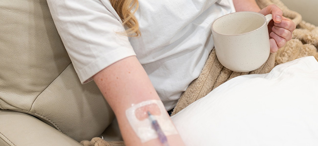 Person with IV in arm and a drink in their hand