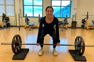 fitness instructor smiling and doing a squat with barbell