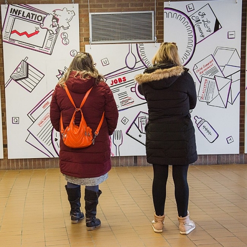 Two women look at the 2023 International Women's Day art installation 'Have a seat at our table'