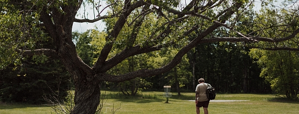 Disc golf player walking towards a target.