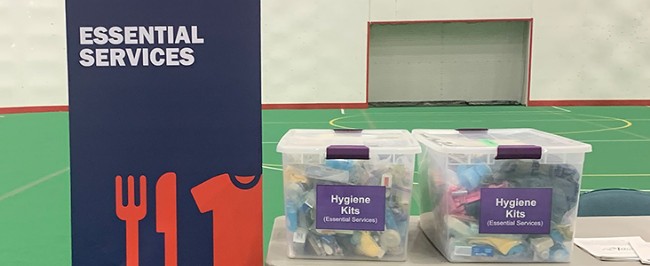 Essential Services banner and two bins of hygiene kits