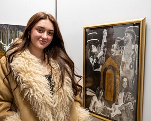 An artist standing beside her visual art