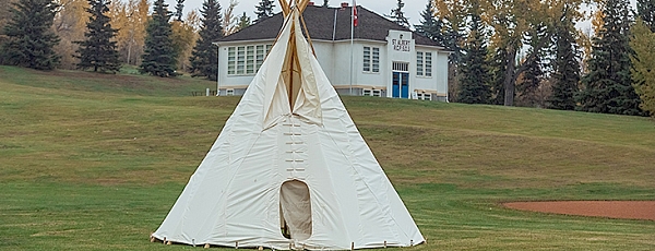 A white tipi in a grass field