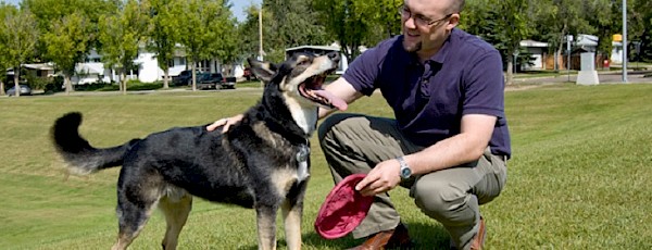Photo of man crouching beside a dog