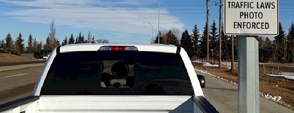 Photo of a white truck beside a sign that says Traffic laws photo enforced