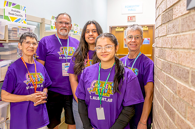 5 volunteers standing next to a brick wall