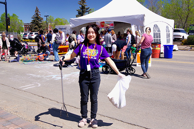 A volunteer wearing a purple shirt cleaning up litter