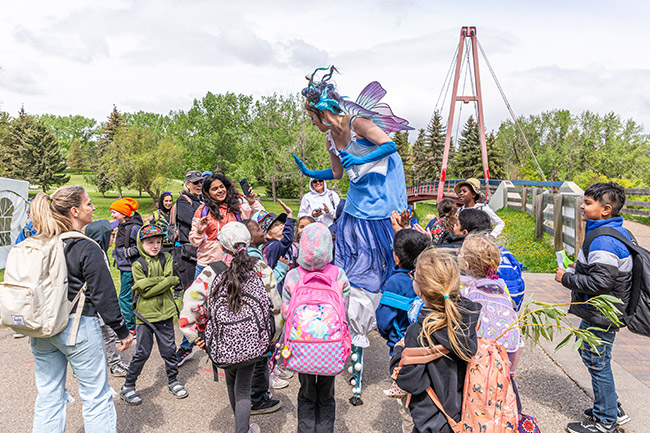 crowd of children around fairy on stilts