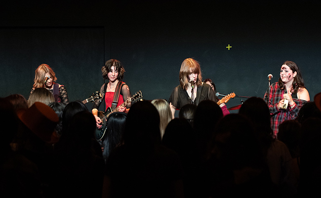 Four performers singing to a crowd