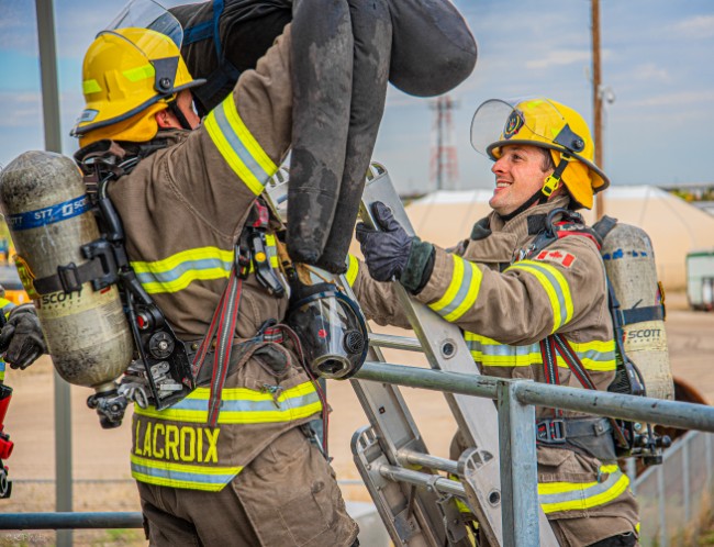 Firefighters passing a dummy on a ladder