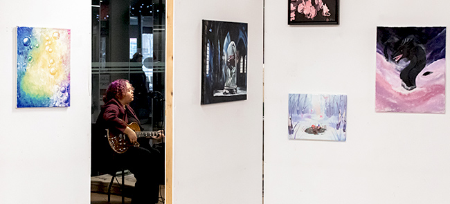 artwork on a wall with musician playing in background