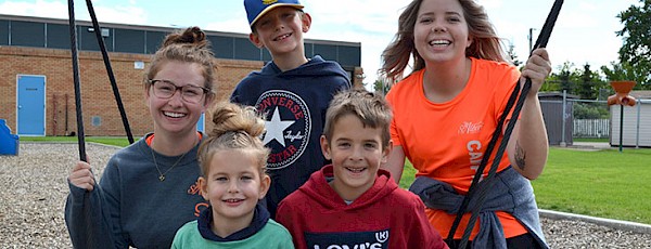 Recreation leaders smiling with three kids on the playground