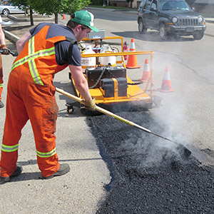 A worker rakes fresh asphalt